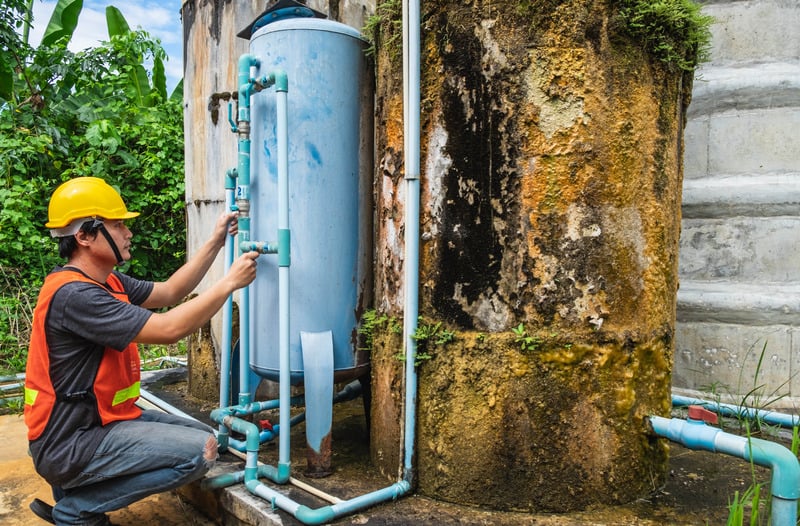 Small garden water tank with tubes integrated in the garden and getting calibrated by a water tank installer